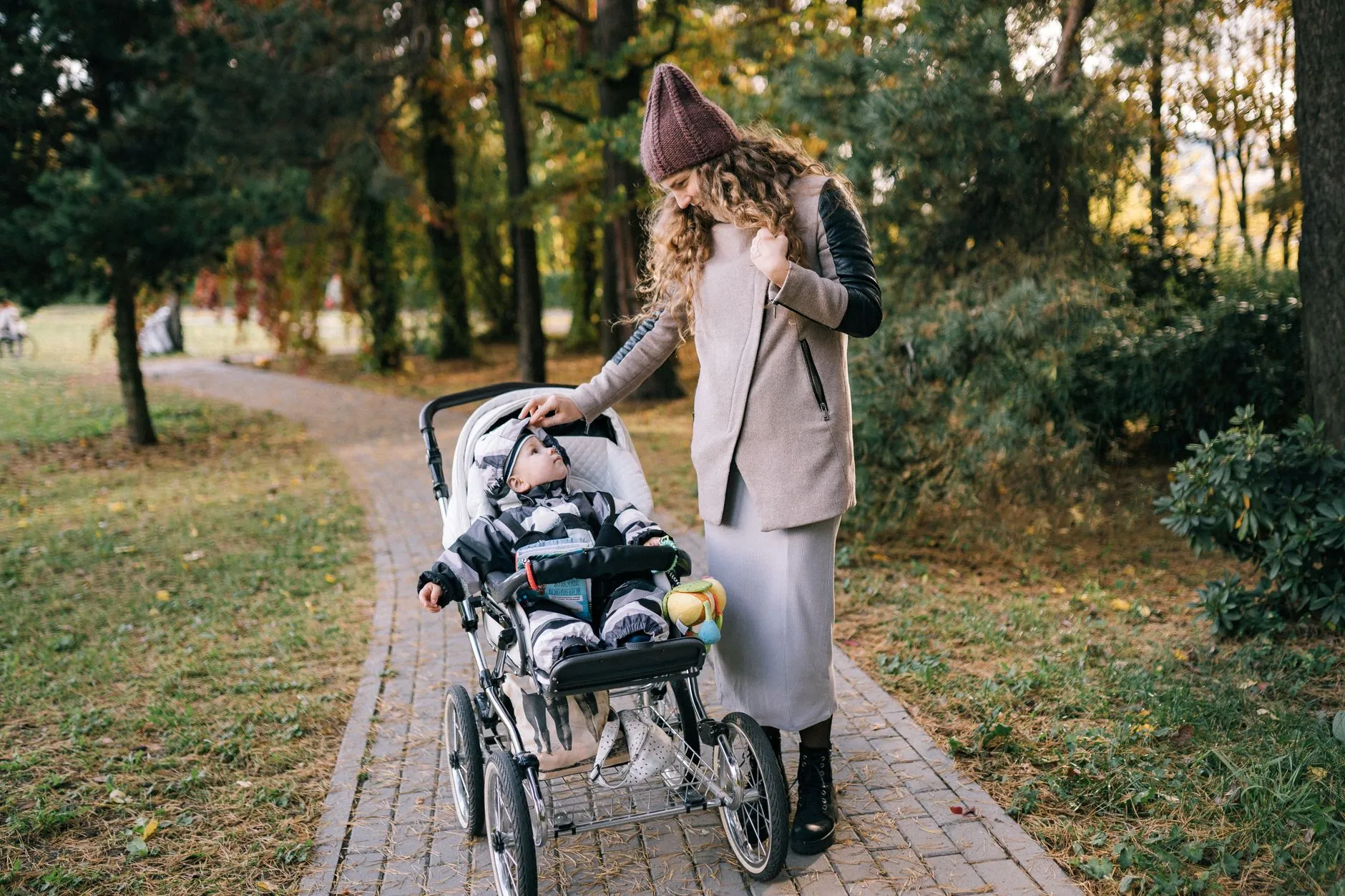 Moeder wandelt met haar baby in de kinderwagen door het park