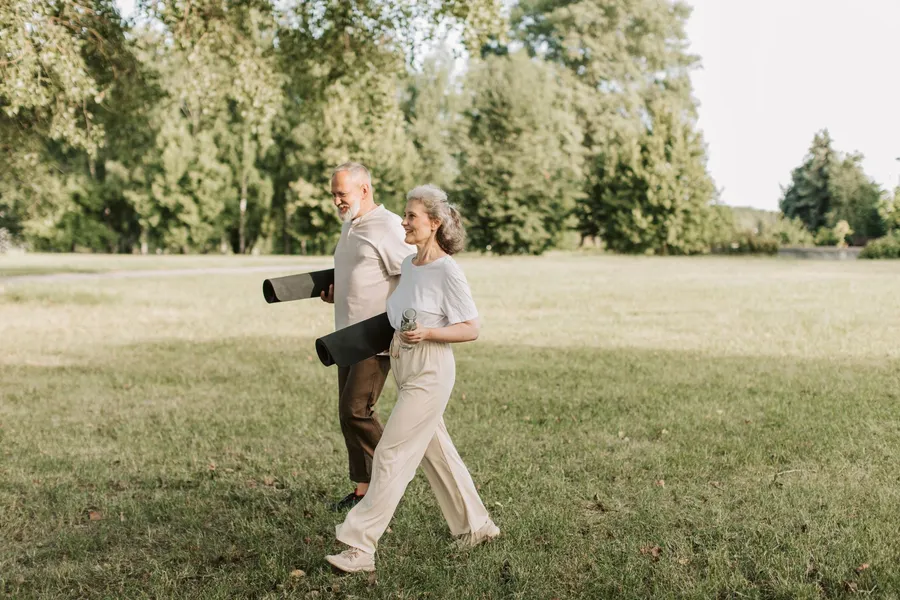 Twee actieve ouderen wandelen samen door een park