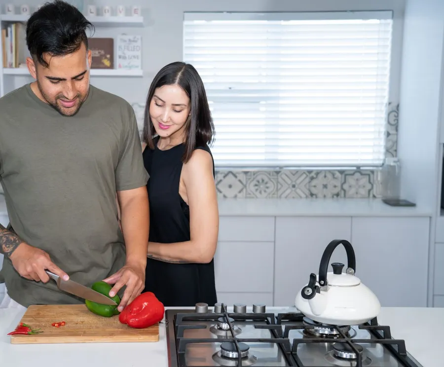 Man snijdt groente met zijn partner in de keuken