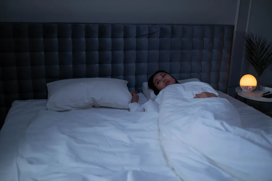 Vrouw ligt wakker in bed in een donkere slaapkamer