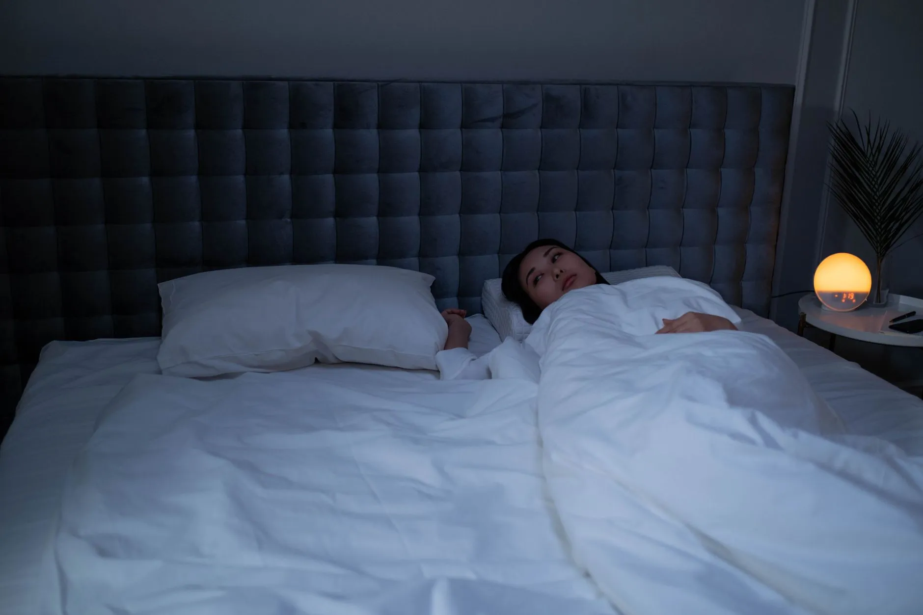 Vrouw ligt wakker in bed in een donkere slaapkamer